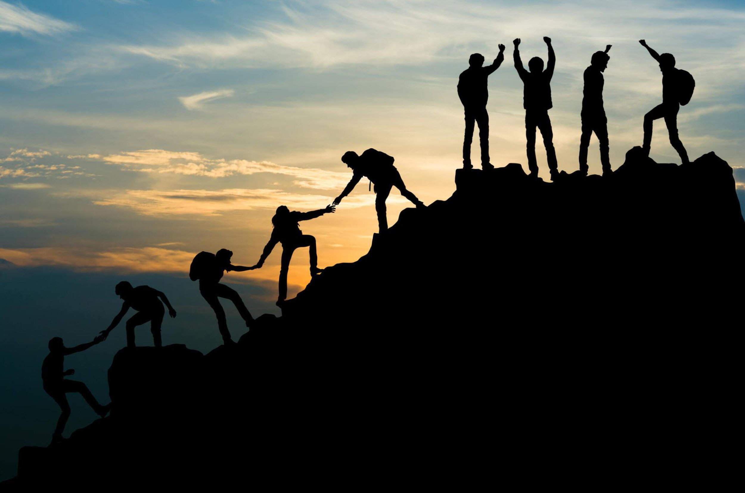 heal relationships and create divine partnerships image of many people holding hands helping each other climb the summit