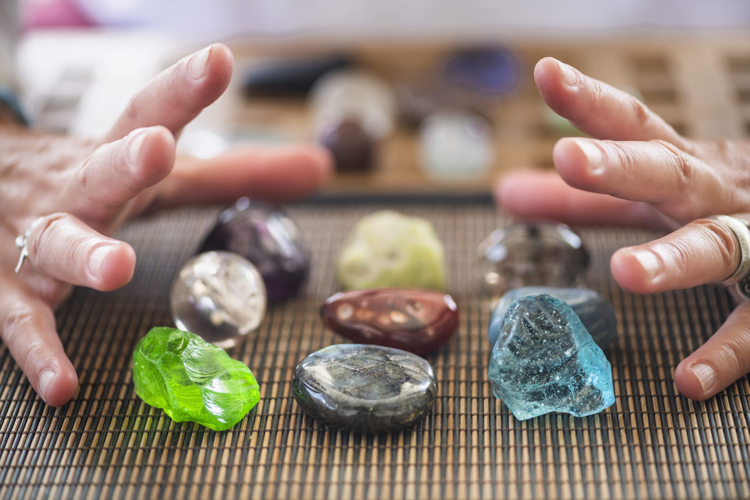 colorful crystals with human hands surrounding them to interact with crystal energies